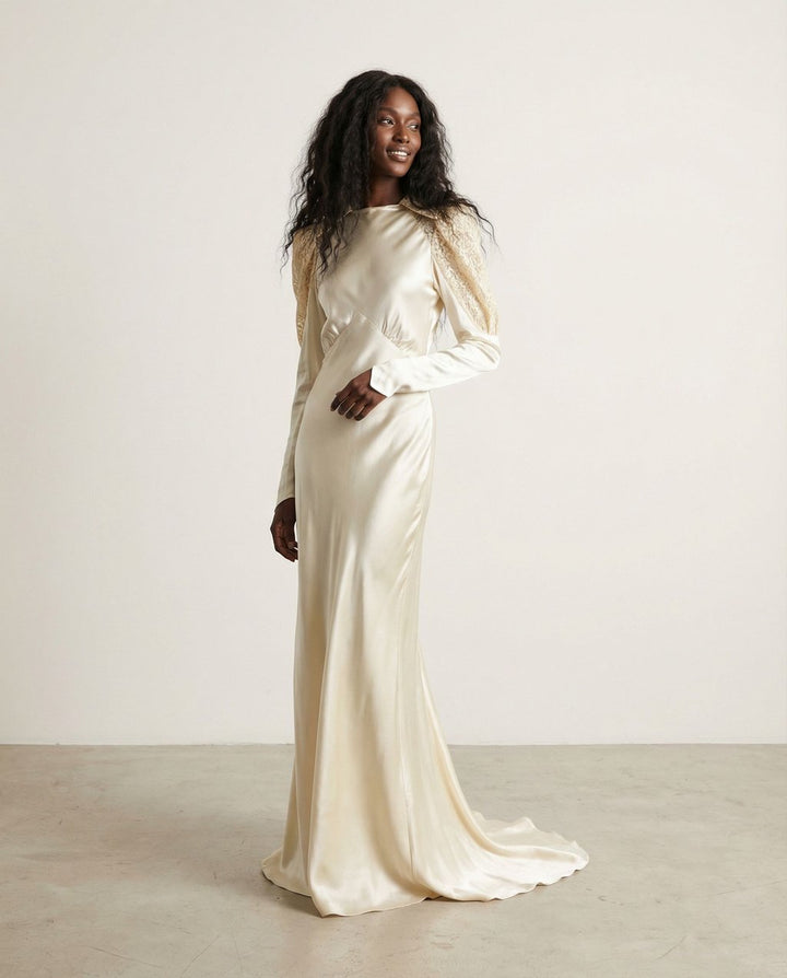 Woman wearing a long, light-colored satin dress against a plain background