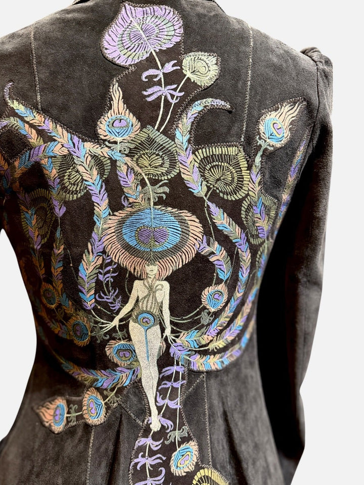 A dark black suede jacket shown from the back, featuring elaborate, colorful hand-embroidered and painted floral, insect, and human figure motifs across the back panel.