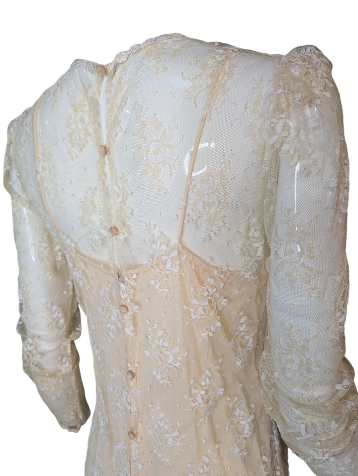 Ivory lace dress with intricate detailing on a white background