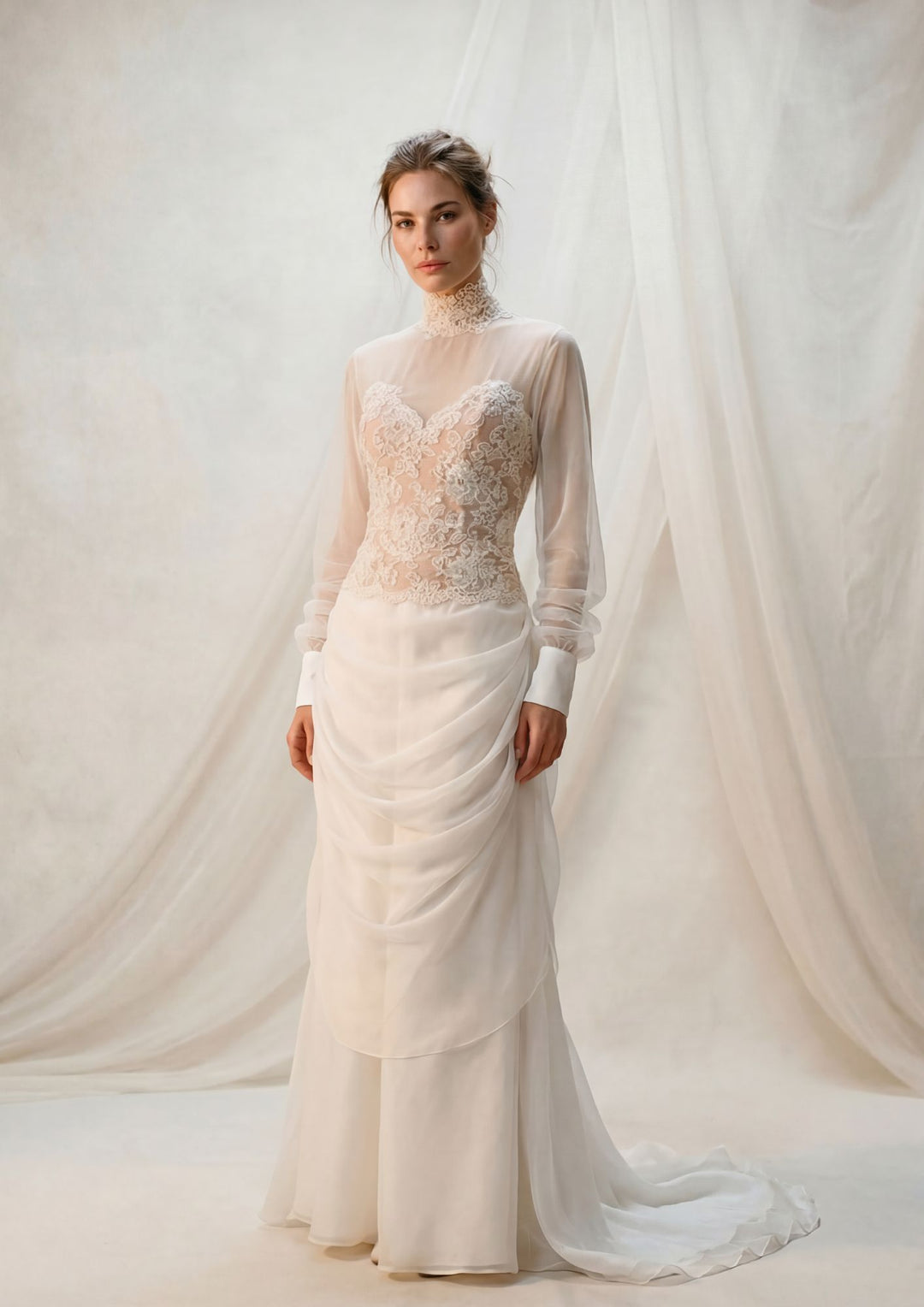 Woman wearing a white wedding dress designed by Bob Mackie for the Diamond Collection  with long sleeves against a white curtain background