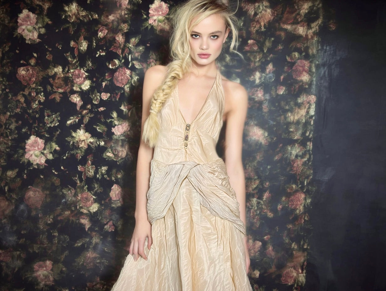 Model in designer vintage champagne silk gown with plunging neckline and draped detailing, styled as vintage bridal elegance against floral backdrop — perfect for a vintage wedding.