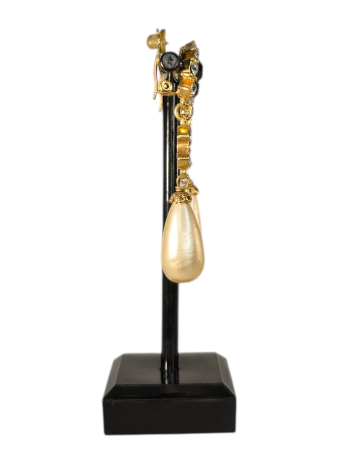 Gold Chanel teardrop earring on a black stand against a white background
