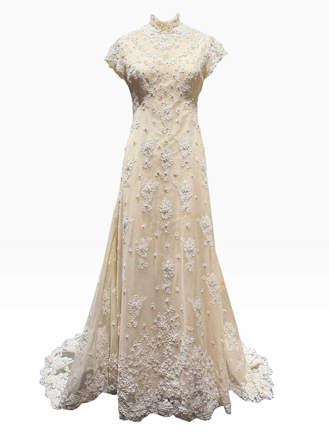 An elegant A-line wedding gown in champagne beige with intricate white floral lace appliques, a high mock neck, and short cap sleeves, shown against a plain white background.