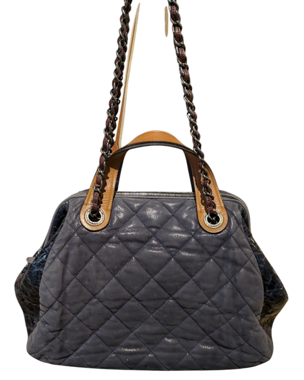 A close-up photo of a Chanel In The Mix tote bag in a vibrant blue color. The bag is made of quilted leather and features a chain-link strap and a gold Chanel logo on the front