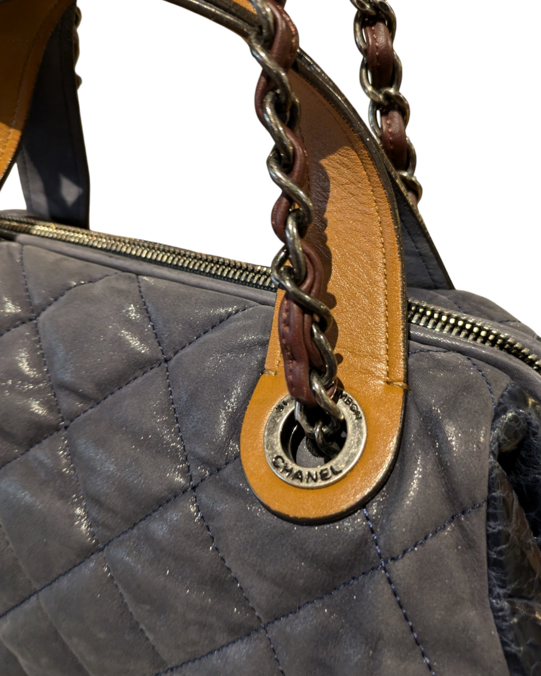 A close-up photo of a Chanel In The Mix tote bag in a vibrant blue color. The bag is made of quilted leather and features a chain-link strap and a gold Chanel logo on the front