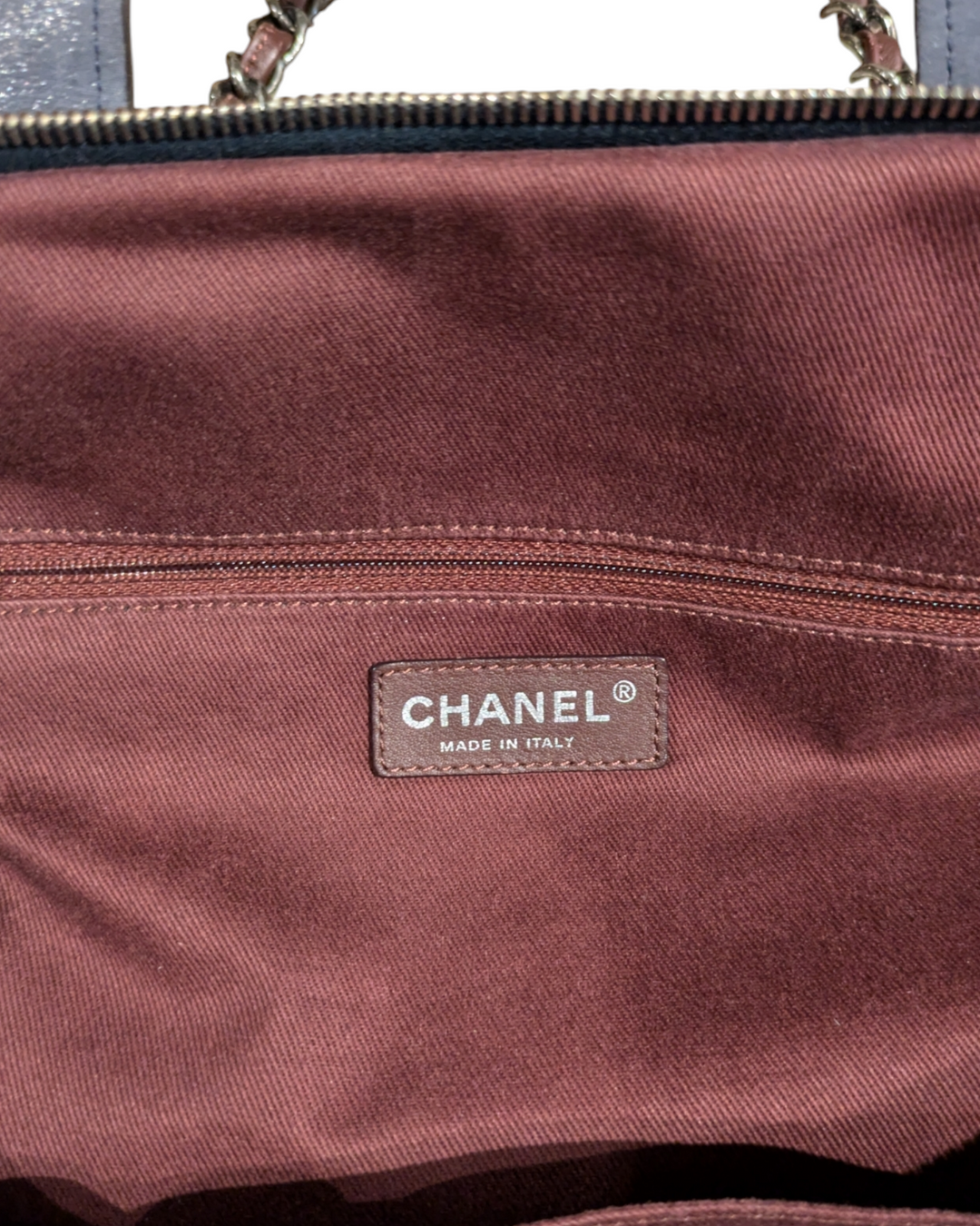 A close-up photo of a Chanel In The Mix tote bag in a vibrant blue color. The bag is made of quilted leather and features a chain-link strap and a gold Chanel logo on the front