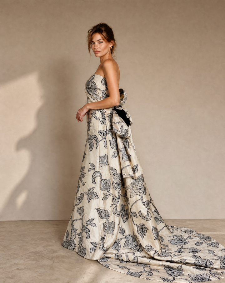 Woman wearing a floral strapless gown against a plain background