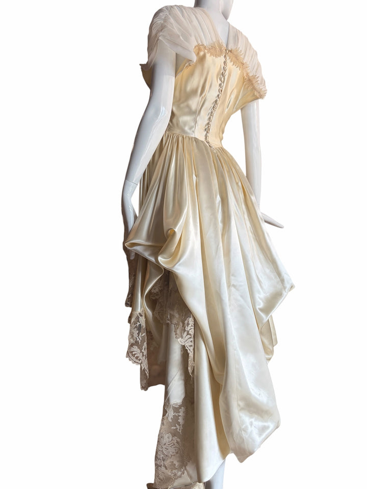 RERACKED cream satin high-low evening gown with lace trim, pleated cap sleeves, and button-up back on a mannequin